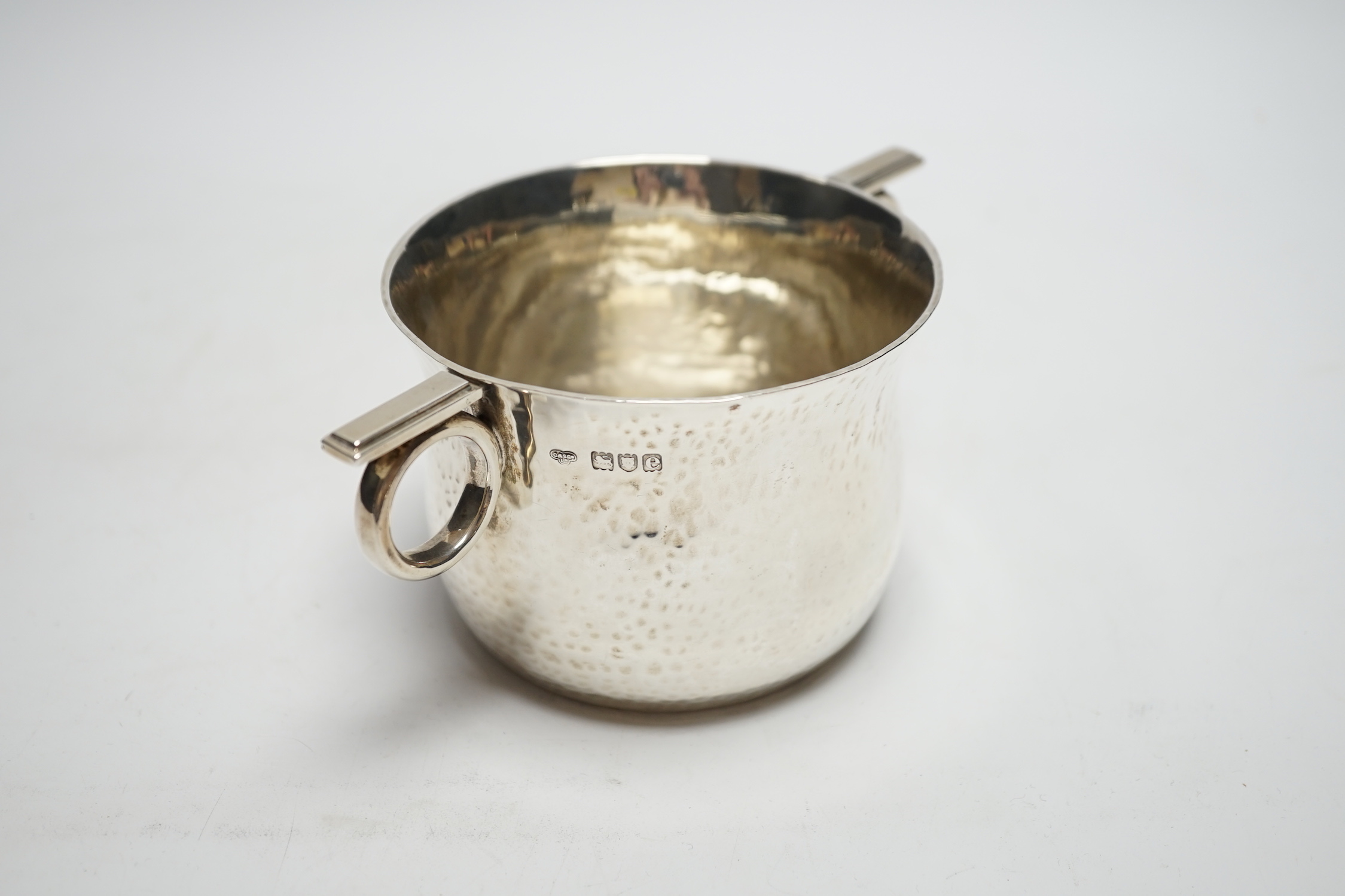 A late Victorian Arts & Crafts planished silver ring handled cup, Goldsmiths & Silversmiths Co Ltd, London, 1900, height 75mm, 8.8oz.